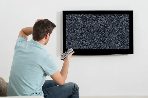 Mann sitzt vor defektem Fernsehgerät