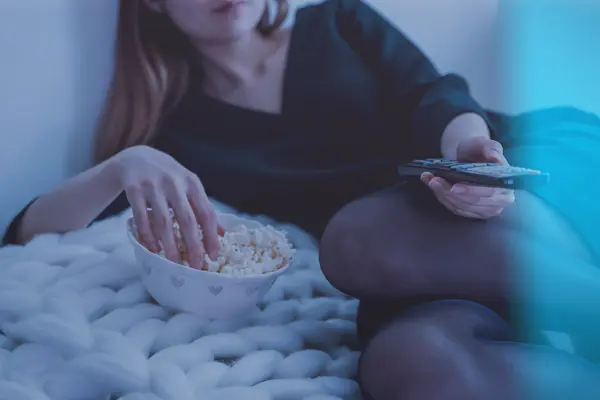 junge Frau schaut TV mit Popcorn