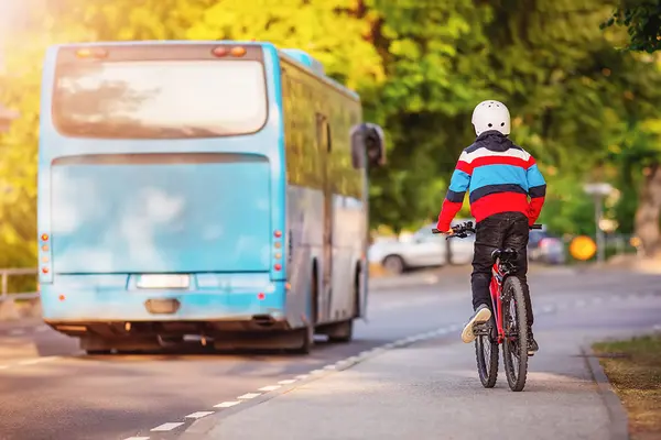 Kind fährt auf Fahrrad hinter einem Bus her