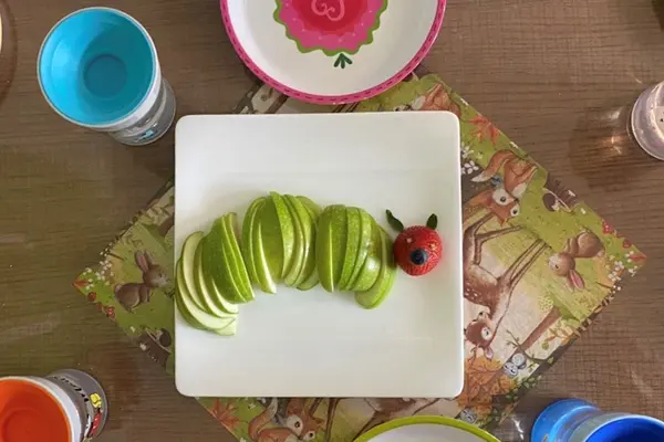 Ein Teller, auf dem aus Obststücken das Bild einer Raupe gelegt ist