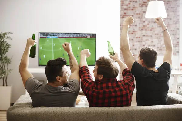 Drei Männer schauen ein Fussballspiel