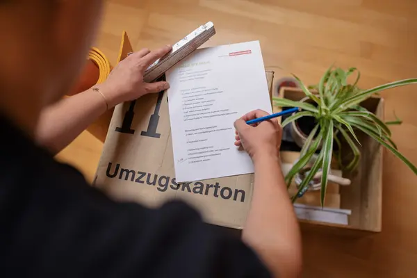 Mann hakt Umzugs-Checkliste auf Umzugskarton ab