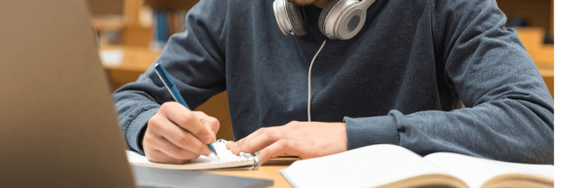 Ein Schüler sitzt in einer Bibliothek vor einem Laptop und lernt