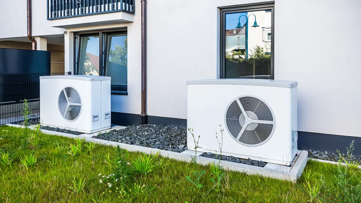 Zwei Wärmepumpen stehen vor der Hauswand eines Mahrfamilienhauses