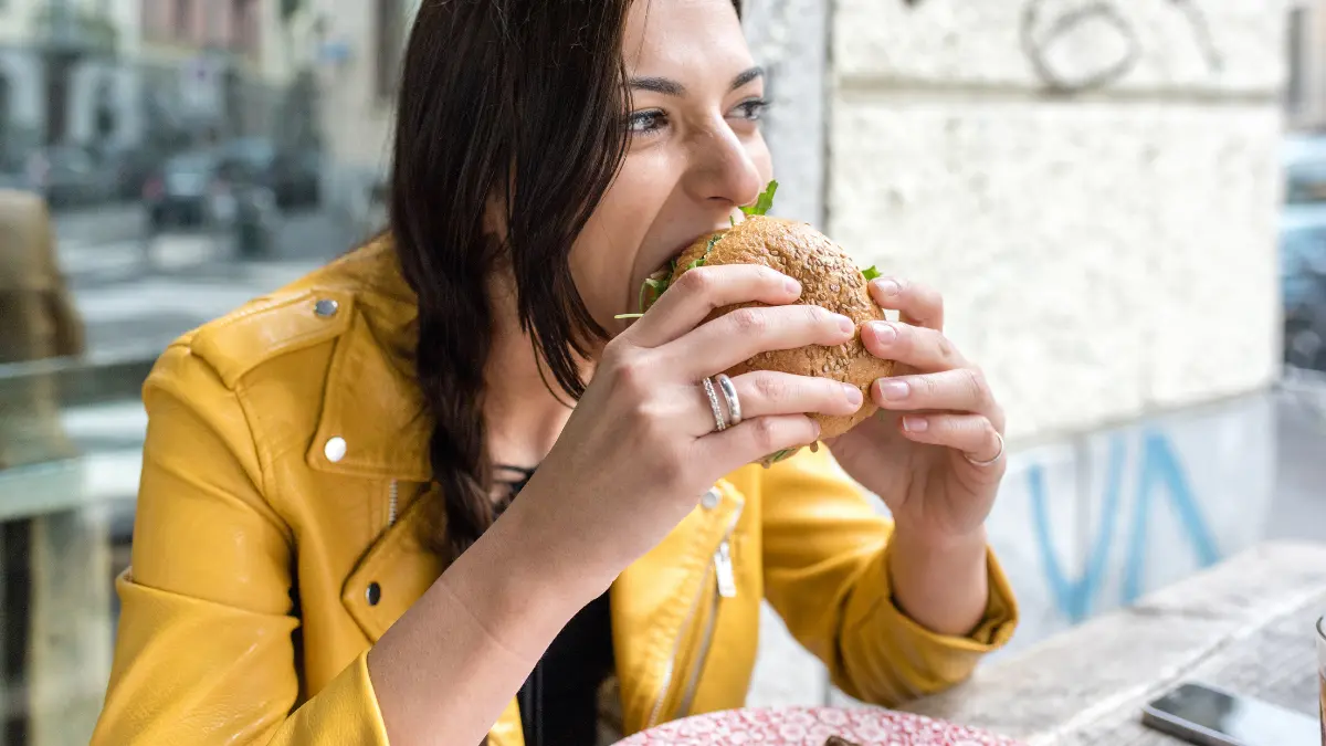 junge Frau beisst in einen Burger