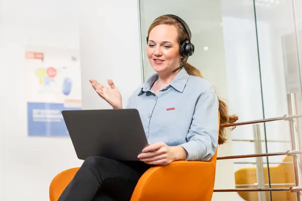 Frau sitzt telefonierend an einem Laptop