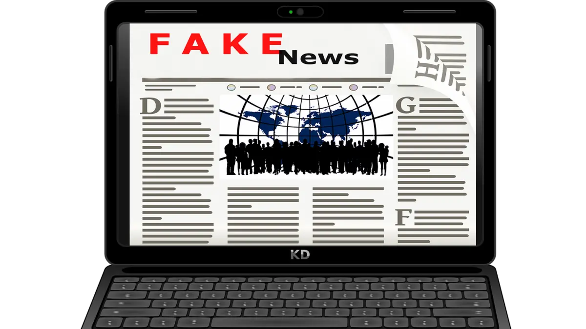 Auf dem Bildschirm eines aufgeklappten Laptops ist das Wort Fake News zu lesen
