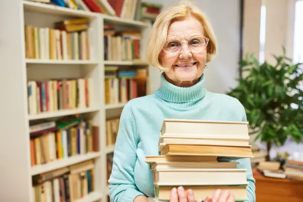 Rentnerin mit einem Stapel Bücher im Arm