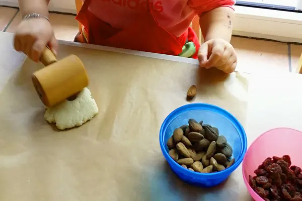 Kinderhände rollen mit einem kleinen Teigroller Hefeteig für Weckmänner