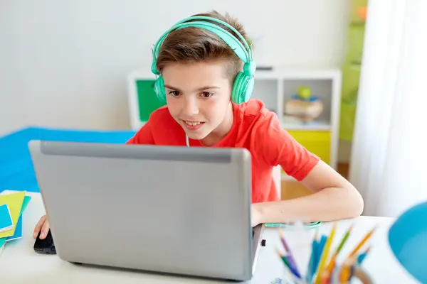 Junge sitzt vor dem Laptop und hat Kopfhörer auf