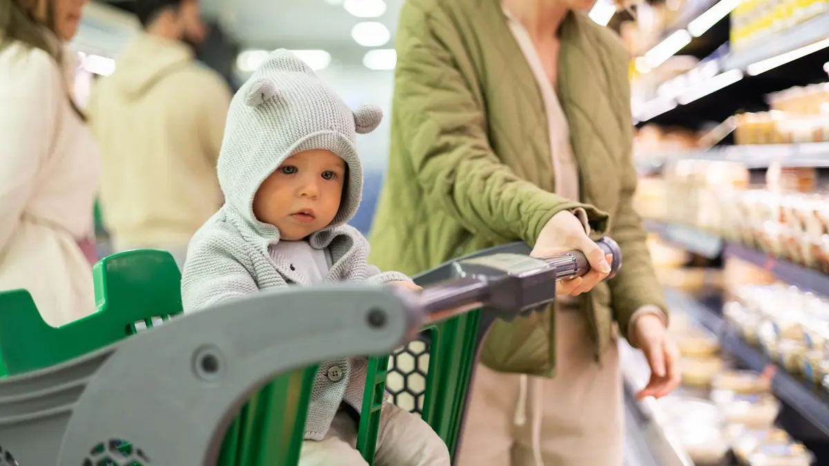 Ein Baby sitzt in einem Einkaufswagen im Supermarkt.