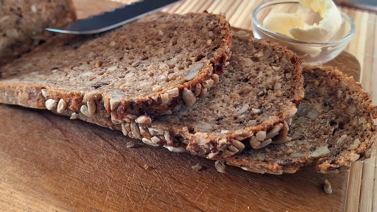 Drei aufgeschnittene Scheiben Brot liegen auf einem Brett.