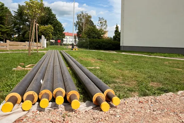 Heizungsrohre liegen vor einem Haus und müssen verlegtwerden.