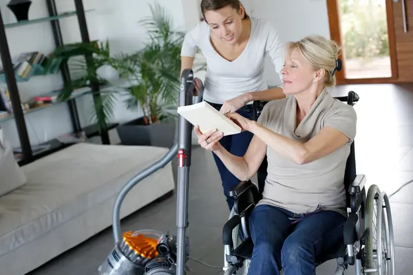 Haushaltshilfe hilft Patientin im Rollstuhl