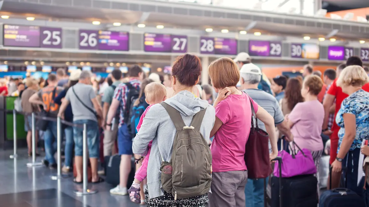 Eine Schlange von Menschen steht vor einem Schalter am Flughafen.