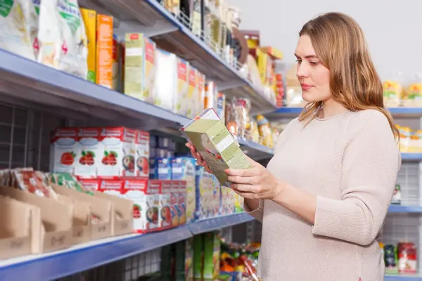 Eine Frau studiert Verpackungen beim Einkaufen in einem Supermarkt.