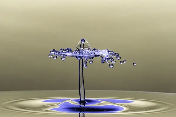 Aufnahme eines farbigen Tropfens, der auf klares Wasser trifft