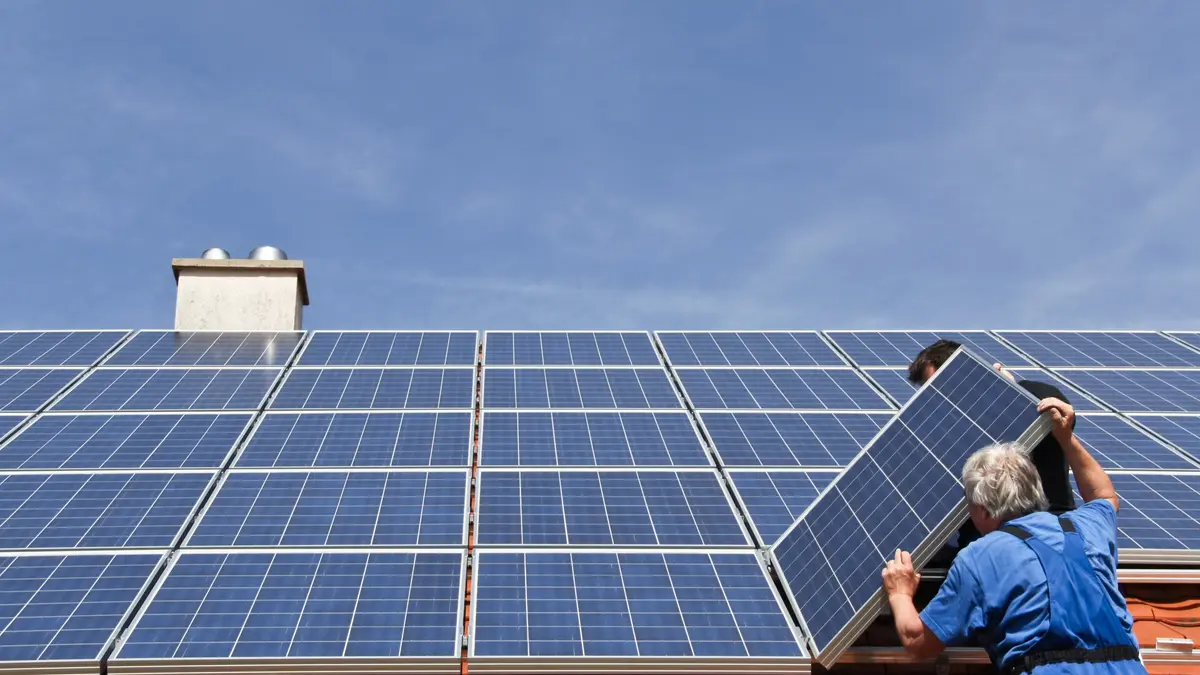 Eine PV-Anlage wird auf einem Dach von Monteuren installiert