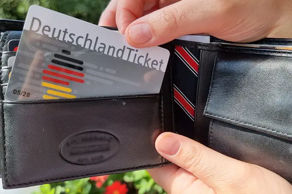 Eine Hand zieht ein Deutschlandticket aus einem Portmonee