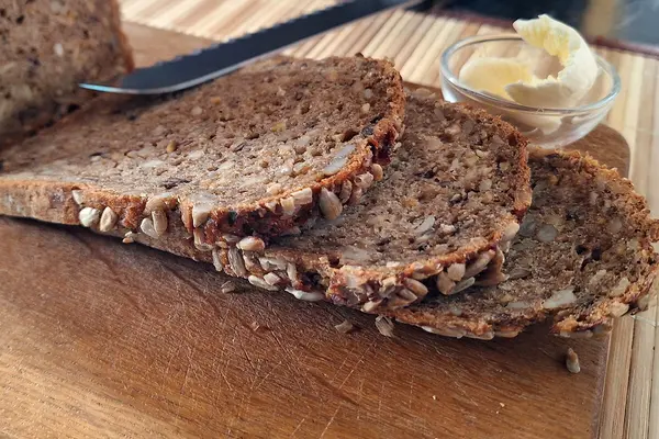Drei aufgeschnittene Scheiben Brot liegen auf einem Brett.
