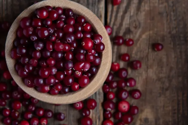 Eine Schüssel mit Preiselbeeren steht auf einem Holztisch.