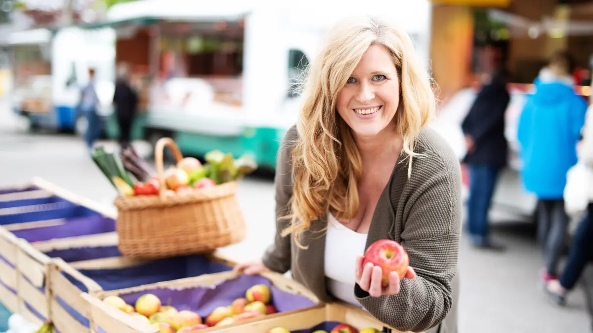 Frau sucht Apfel aus Kiste