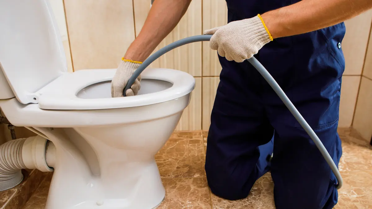 Handwerker reinigt Toilette mit Schlauch