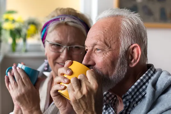 Senioren sitzen und trinken aus den großen Tassen