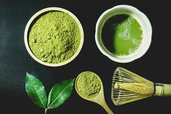 Matcha-pulver mit schneebesen und portionsloeffel, grünes Matchablatt