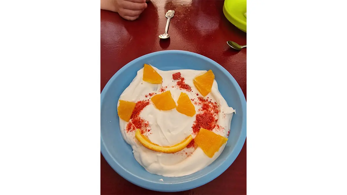 Quarkspeise mit Orangen formt eine Sonne mit Gesicht