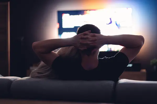 Ein Paar sitzt auf dem Sofa und schaut fern.