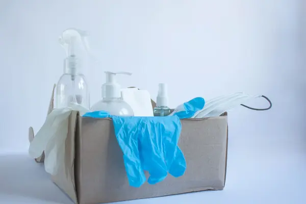 Karton mit Pflegemitteln wie Einmalhandschuhen, OP-Maske, Spray