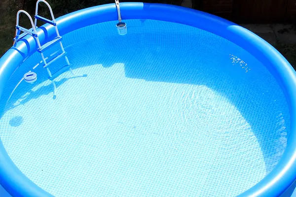 Blauer aufblasbarer Pool mit Wasser gefüllt und Leiter im Garten