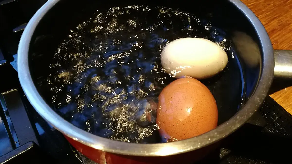 Ein Topf mit kochendem Wasser und zwei Eiern
