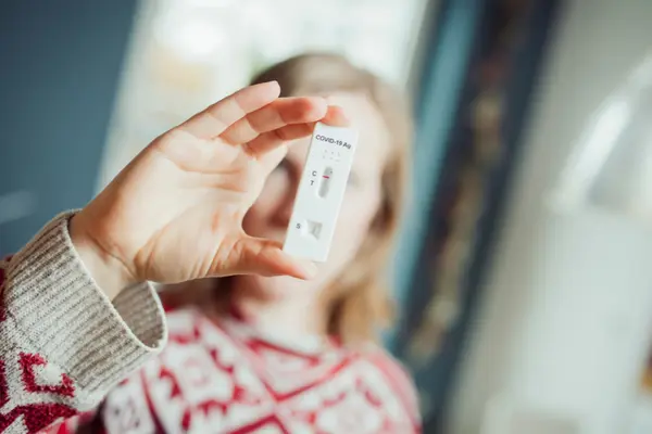 junge Frau hält eine Testkassette vor ihr Gesicht