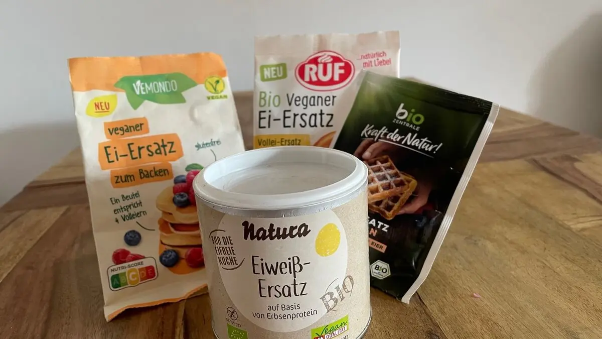 Verschiedene Ei-Ersazprodukte in ihren Verpackungen auf einem Holztisch.
