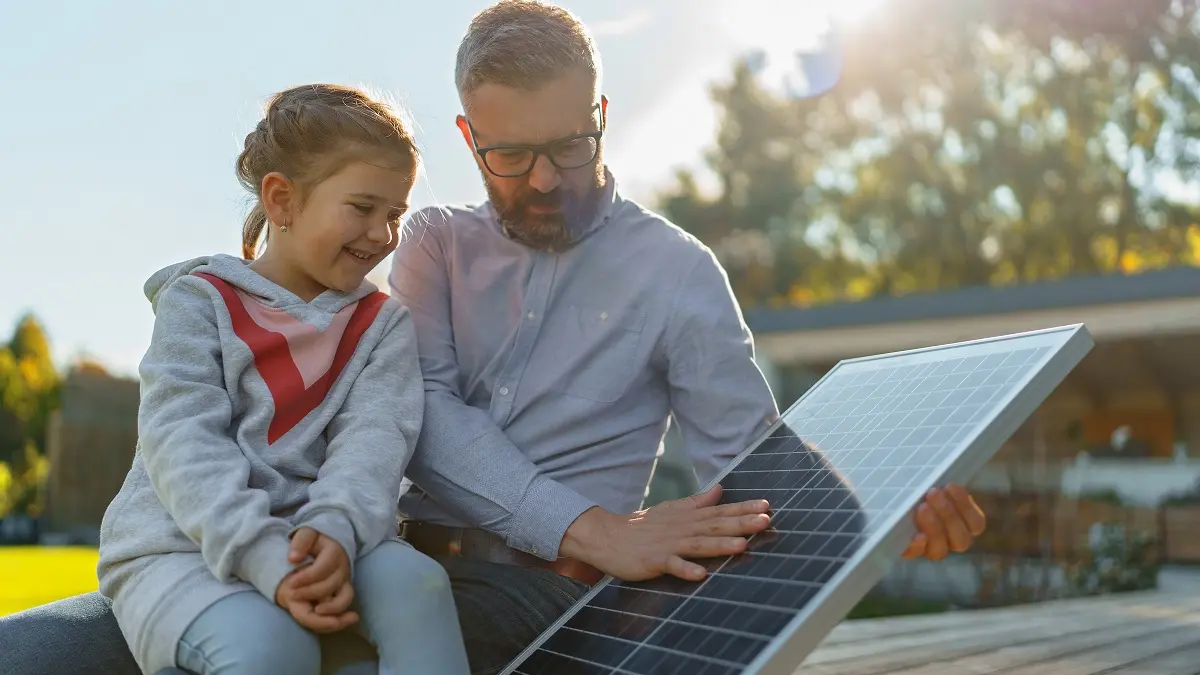 Vater und Tochter schauen sich ein Solarmodul für den Balkon an.