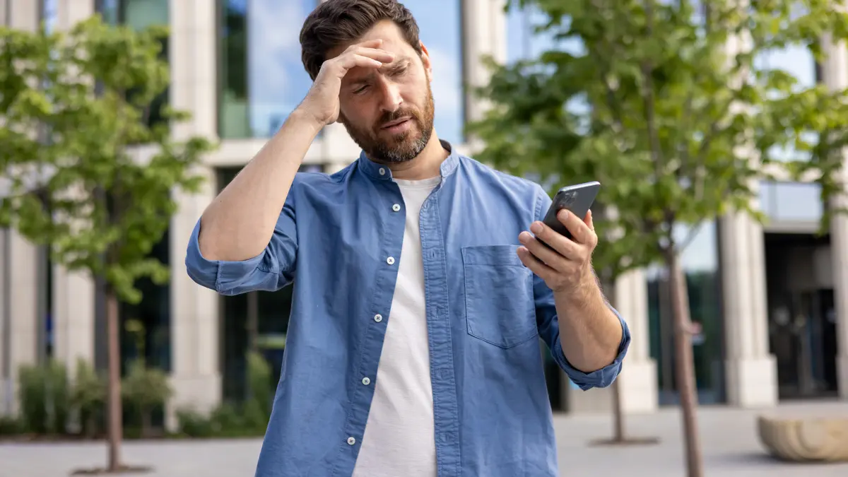 Mann schaut verärgert auf sein Smartphone.