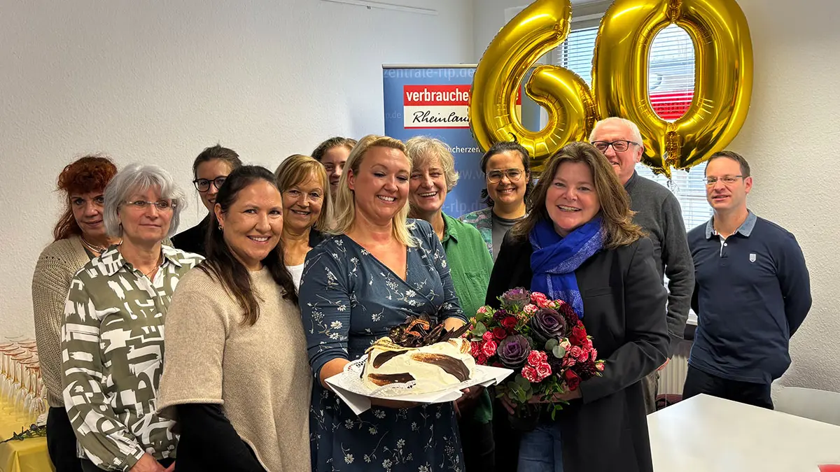 Eine Gruppe aus fröhlichen Menschen, die einen Kuchen in die Kamera halten