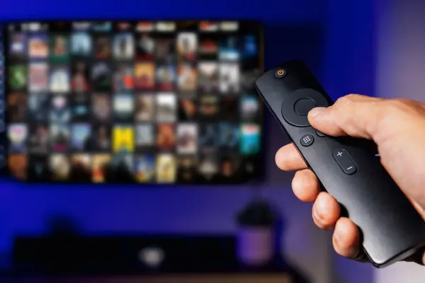 Hand mit Fernbedienung zeigt auf Fernseher