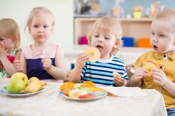 Kindergruppe isst Obst im Kindergarten Esszimmer