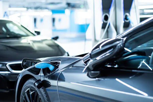 Zwei Elektroautos stehen sich gegenüber, eins wird geladen.