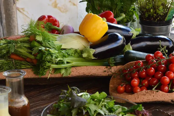 Auf einem Tisch liegen mehrere Gemüsesorten - Tomaten, Auberginen, Fenchel, Paprika, Sellerie