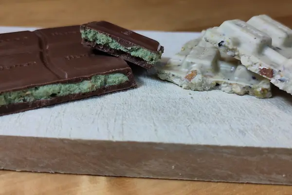 Stücke von Vollmilch- und weißer Dubaischokolade auf einem Schneidebrett