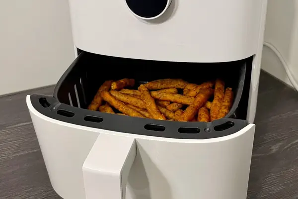 Eine geöffnete Heißluftfritteuse mit Blick auf frittiertes Gargut. 