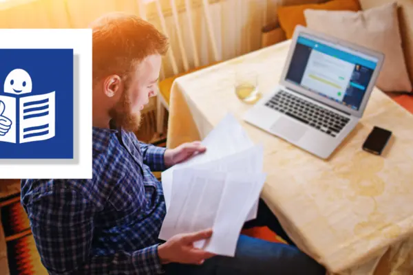 Ein Mann sitzt am Schreibtisch mit Papier und Computer, daneben das Bild für Leichte Sprache
