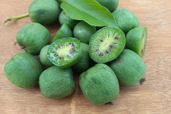 Kiwiebeeren liegen auf einem Holztisch. Eine davon ist halbiert.