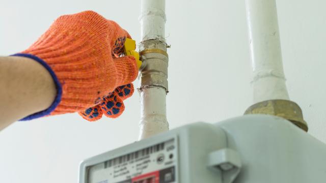 Mensch mit Handschuh dreht Gashahn 