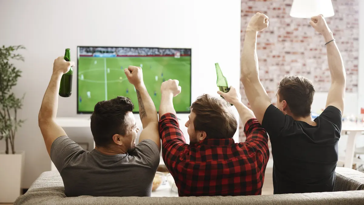 Drei Männer schauen ein Fussballspiel