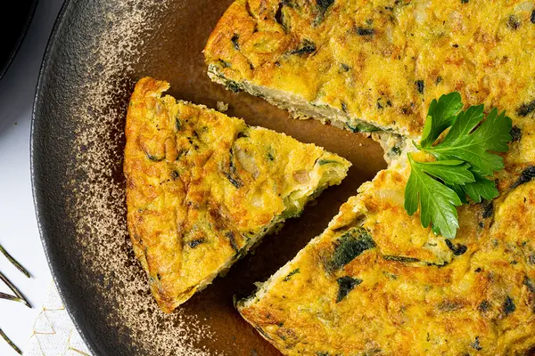 Frittata auf einem Teller, ein Stück ist herausgeschnitten